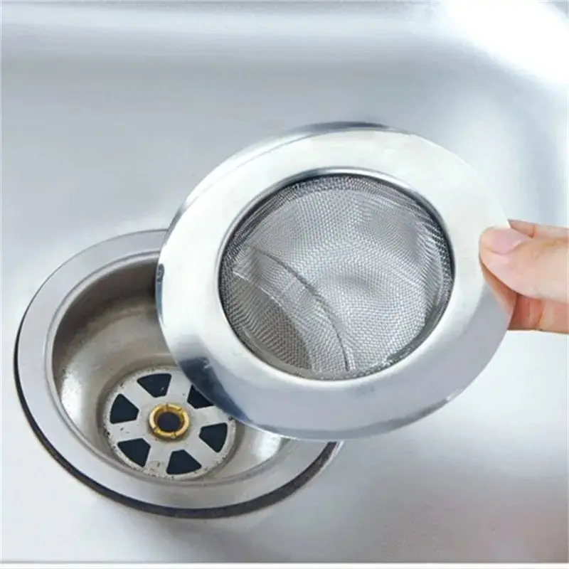 Metallisches Haarsieb mit feinem Netz wird von einer Hand über einen Spülenabfluss gehalten